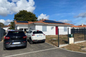 Maison moderne à Angresse avec panneaux solaires sur le toit, deux voitures garées devant et ciel partiellement nuageux.